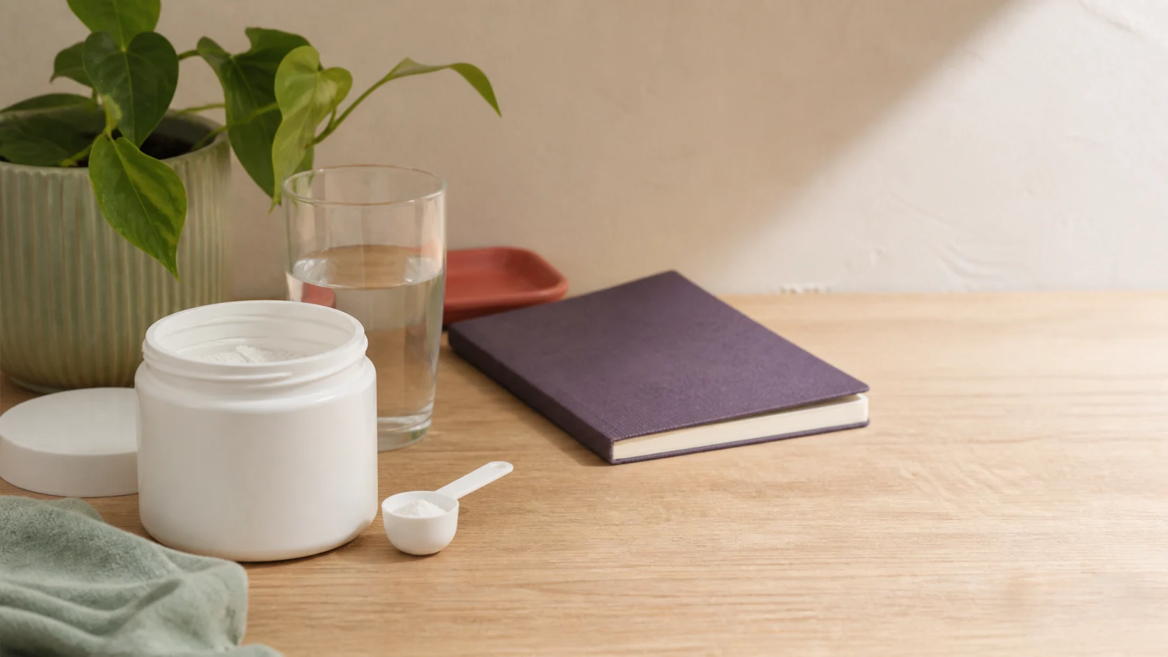 Tarro sin marca, cuchara medidora y vaso de agua sobre una mesa